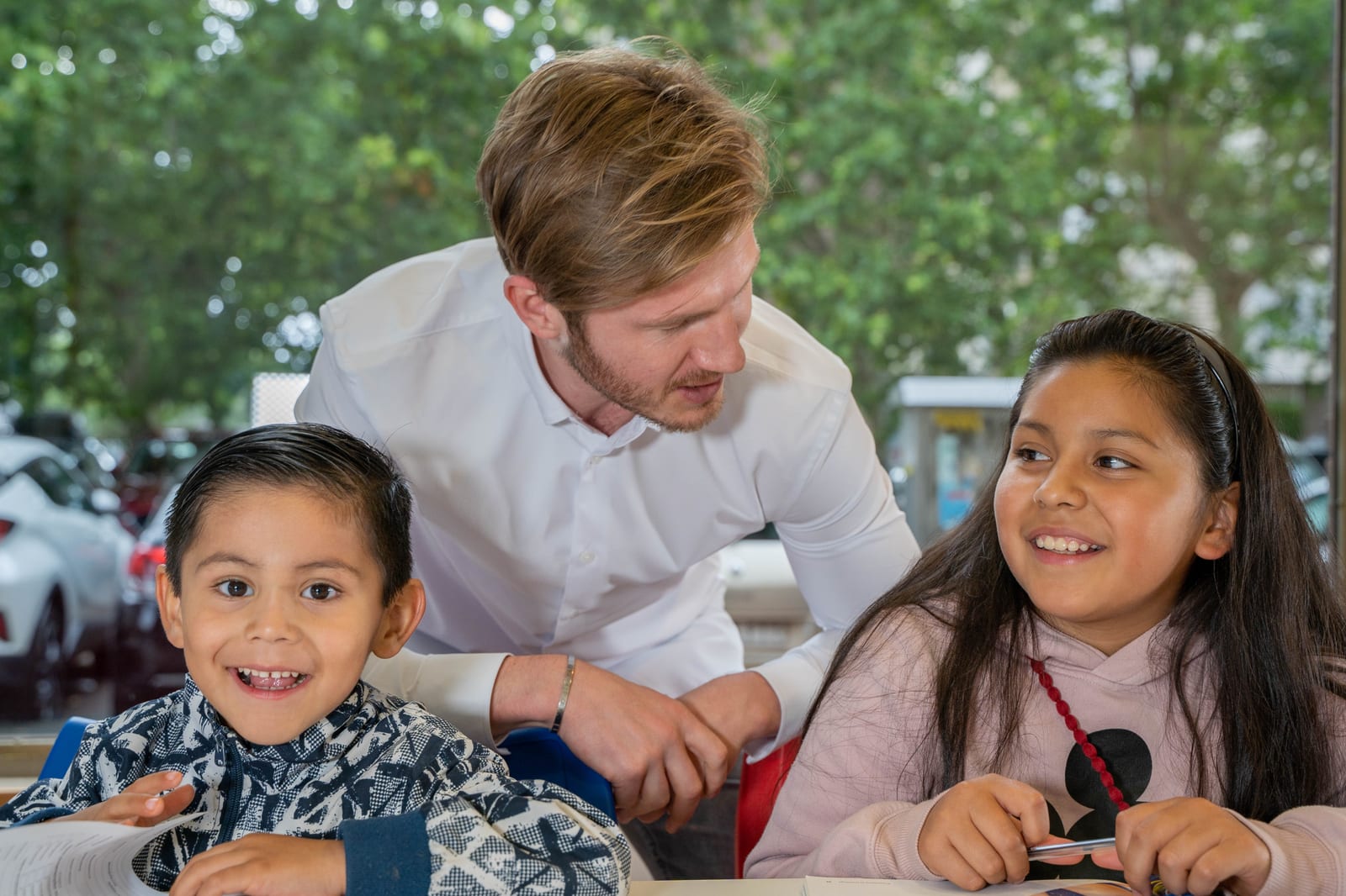 Un profesor de Impulse English Academy ayuda a dos alumnos de infantil durante una clase de inglés